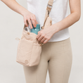 Load image into Gallery viewer, Ivory bottle bag worn crossbody with bottle access on a warm neutral background
