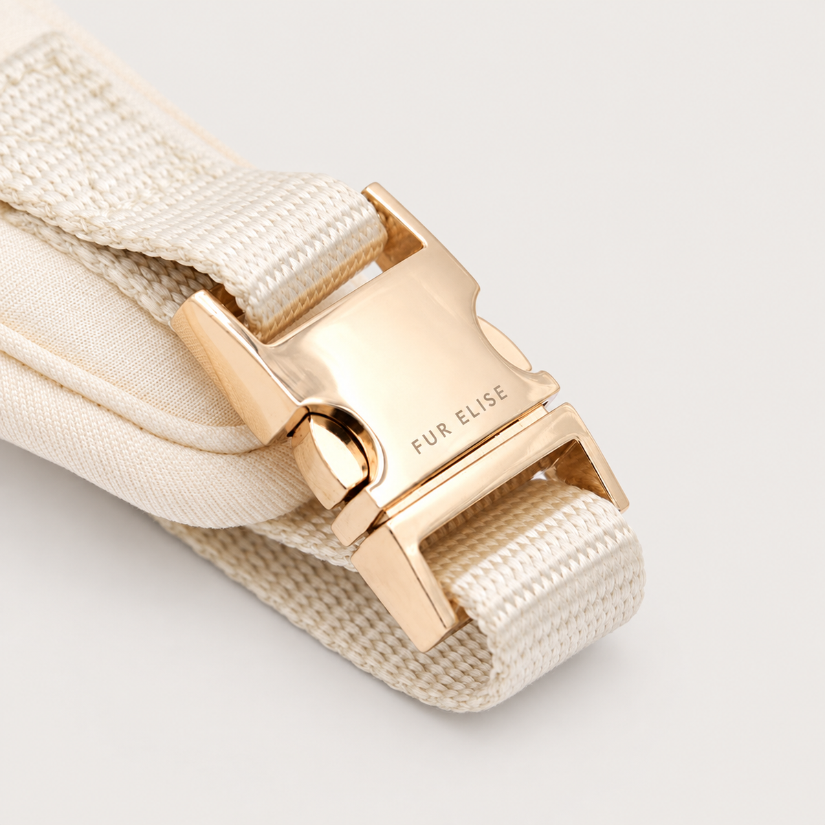 Bone Signature Harness buckle view on a pale warm-gray background