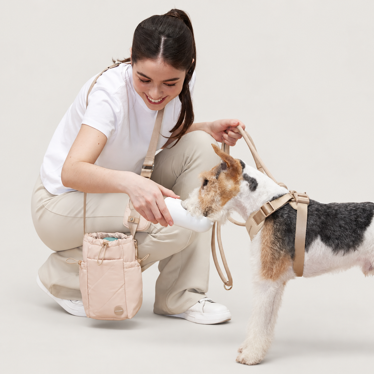 Ivory bottle bag in use while giving a dog water on a warm neutral background